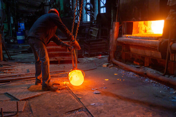 кузнечный рабочий завода, движущийся светящийся металлический заготовка с цепным краном