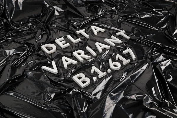 words delta variant B.1.617 laid with silver metal letters on crumpled black plastic bag background in diagonal perspective