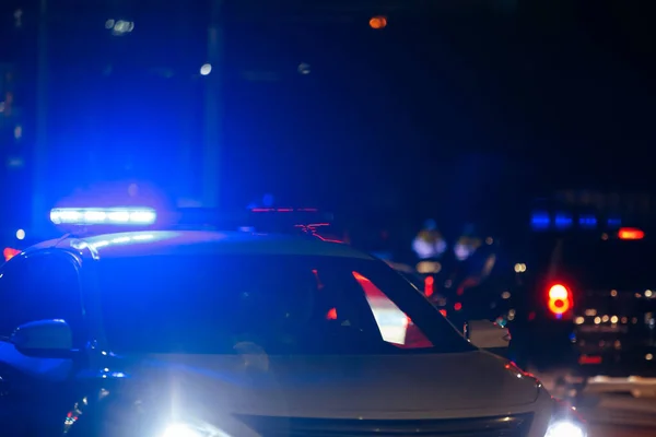 Uneinholbarer Straßenpolizist mit eingeschaltetem roten und blauen Sirenenlicht auf dem Dach auf nächtlicher Stadtstraße — Stockfoto