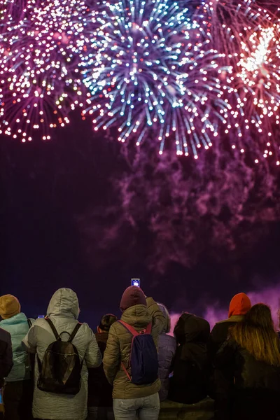 Zicht van achteren op mensen in wark kleding schieten vuurwerk op de telefoon in de koude nacht. — Stockfoto