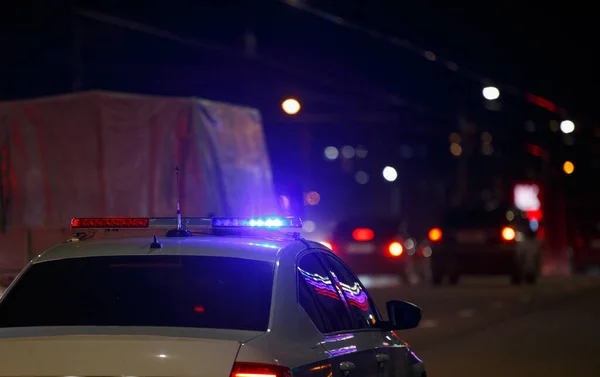 Voiture de police de route inreconizable avec feu rouge et bleu allumé sur son toit sur la route de la ville de nuit — Photo