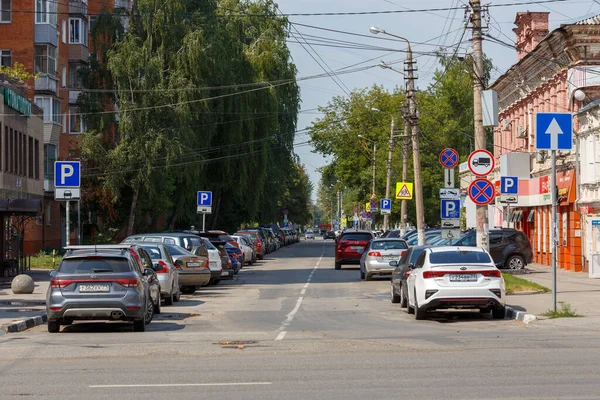 Tula, Rusia - 2 de agosto de 2021: señales de tráfico abrumadoras a lo largo de la estrecha calle de la ciudad de verano a la luz del día con muchos junto con los coches estacionados. — Foto de Stock