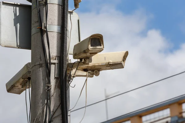 two old cctv security surveillance cameras on street light pole on blue sky background