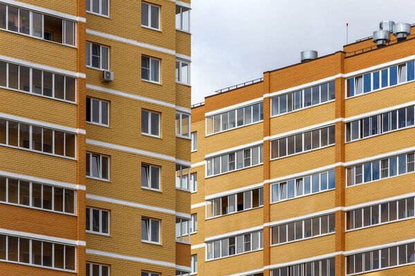 New high rise yellow-orange brick apartment buildings at cloudy day light, close-up telephoto view.