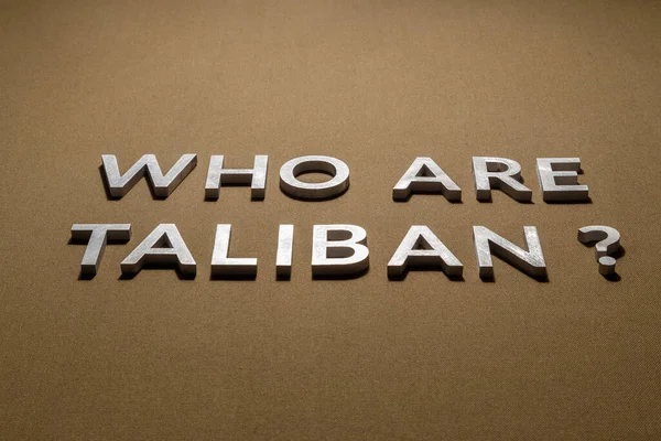 Pytanie, kim są talibowie złożone srebrnymi metalowymi literami na surowej tkaninie płóciennej khaki tan — Zdjęcie stockowe