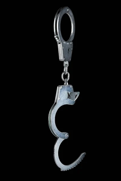 Prawdziwe ocynkowane stalowe kajdanki policyjne półotwarte kluczem wiszącym pionowo, izolowane na czarnym tle — Zdjęcie stockowe