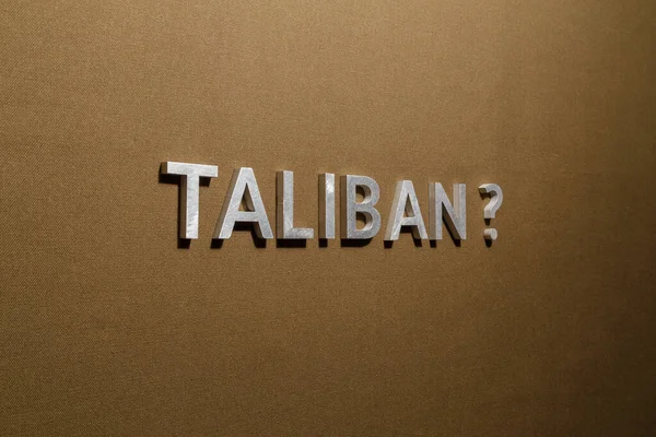 La domanda talebana posta con lettere in metallo argentato su tessuto di tela kaki abbronzato grezzo — Foto Stock