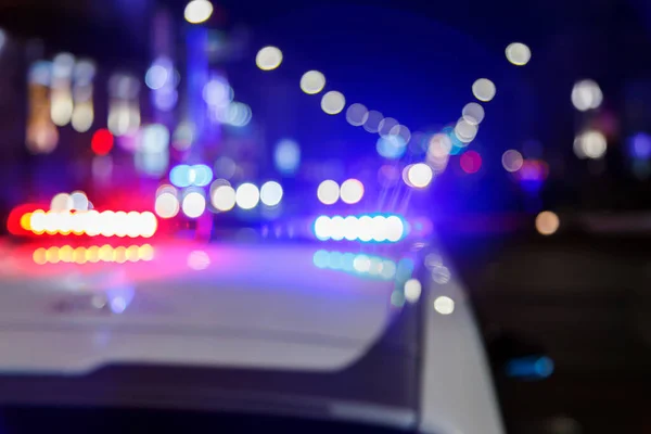 Foto desfocada de luzes de carro da polícia na cidade noturna com foco seletivo e bokeh — Fotografia de Stock