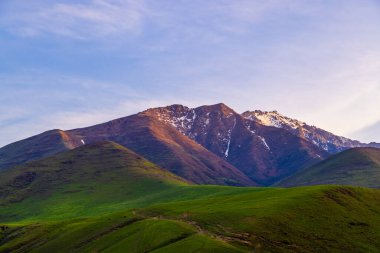 Serene view of majestic mountains standing tall against a clear blue sky in Kyrgyzstan. Peaceful atmosphere invites contemplation and connection with nature.