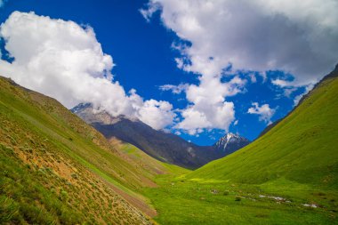 Stunning view of majestic mountains surrounding a tranquil valley with a flowing stream in Kyrgyzstan