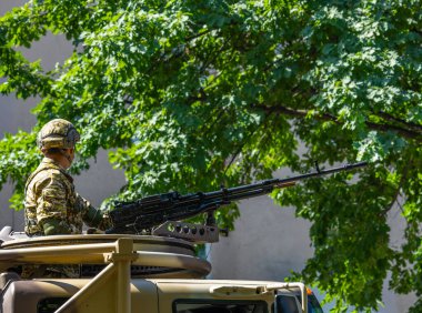 Soldier holds heavy machine gun mounted on vehicle during military operation.