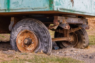 Weathered rusty trailer with two wheels rests on grassy area during daytime. Rustic charm and aged texture evoke a sense of nostalgia and tranquility in nature.