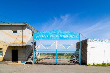 Blue gate at tan building in national sports games venue, kok-boru stadium in Sokuluk, Kyrgyzstan - May 2, 2024