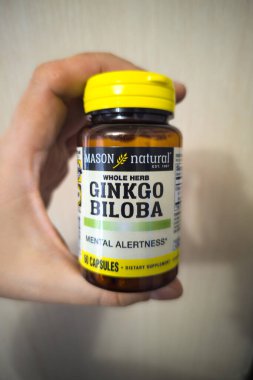 white hand holding a bottle with Ginkgo Biloba supplement in Sokuluk, Kyrgyzstan - March 26, 2024