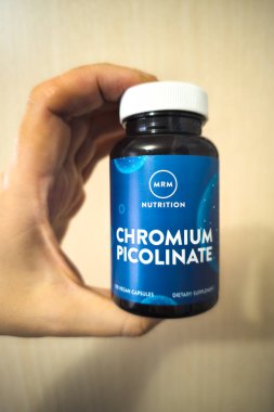 Close-up of a hand holding a bottle of MRM Chromium Picolinate vegan capsules, a dietary supplement in Sokuluk, Kyrgyzstan - March 26, 2024