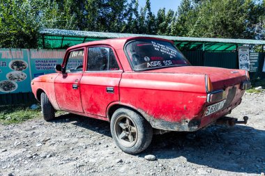 A red Moskvich 412 car parked on a gravel lot in Kyrgyzstan. The car is a classic Soviet-era vehicle, a symbol of a bygone era. Sokuluk, Kyrgyzstan - September 1, 2023