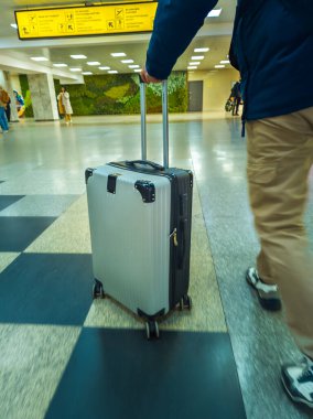 A man pushes a rolling suitcase through a brightly lit Manas airport terminal in Bishkek, Kyrgyzstan - March 2, 2024