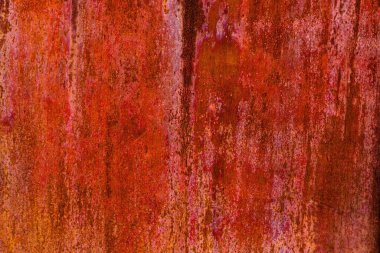 Uniformly rusted reddish-brown metal surface with vertical streaks of darker oxidation