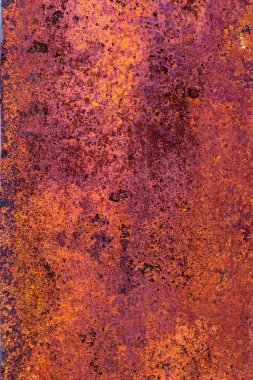Metal surface with a thick layer of rust, exhibiting a predominantly purple hue with hints of orange and a rough texture