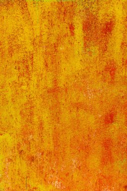 Close-up of a weathered rusty metal surface with a vibrant orange and yellow texture. The corroded iron shows peeling paint and oxidation, creating an abstract industrial background with a rough, aged appearance.