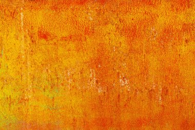 Close-up of a weathered rusty metal surface with a vibrant orange and yellow texture. The corroded iron shows peeling paint and oxidation, creating an abstract industrial background with a rough, aged appearance.