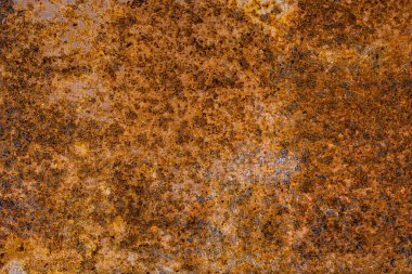 Close-up shot reveals a heavily rusted metal surface, showcasing significant corrosion and a textured, aged appearance. The predominantly brown and orange hues highlight the oxidation and weathering of the iron or steel material.