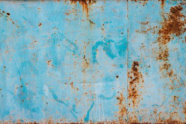 rusted blue metal with corrosion and an aged, textured surface. Brown rust contrasts with the remaining blue paint.
