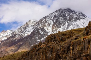 Vast snow-capped mountain range stretches across the horizon under clear blue sky. Serene outdoor setting evokes feelings of tranquility and majesty in nature.