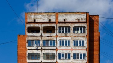 Weathered building stands prominently in cityscape, showcasing multiple rounded windows and balconies.