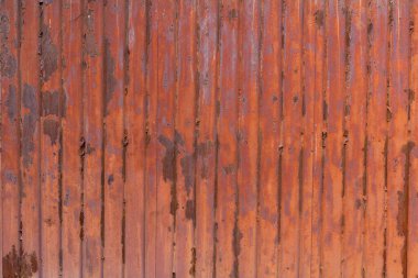 Kırmızımsı kahverengi pas kaplı kıvrımlı metal bir levhanın yakın plan görüntüsü.