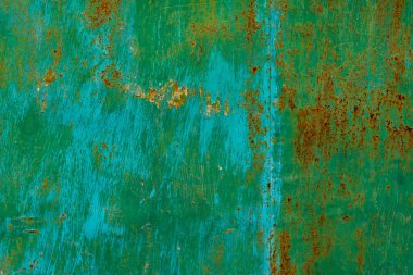 Yıpranmış yeşil metal yüzey pas ve aşınma sergiliyor, karmaşık dokular sergiliyor. Açık hava endüstriyel ortamları gün ışığında grunge havasını arttırır..