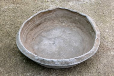 Weathered dented gray aluminum basin on concrete floor. This basin is for manual concrete mixing.