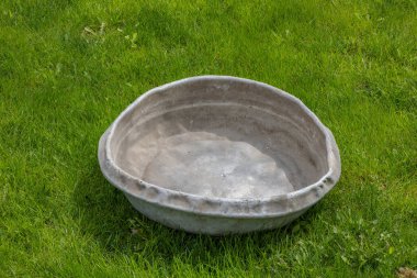 Yeşil çimenlikteki yıpranmış gri alüminyum leğen. Bu leğen elle beton karıştırmak için..