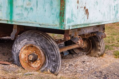Eski, paslı bir karavan kırsal bir alanda yerde terk edilmiş duruyor. Yıpranmış dış görünüş, gündüz güneşinin altında yıllarca süren ihmalkarlığı yansıtır..