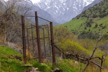 Kırgızistan 'ın dağlarında döner kapılı paslı tel örgüler. Bu kapı sığırların geçmesini engelliyor ama insanlara yol açıyor..