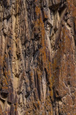 Dağlık bir açık havada engebeli kaya oluşumu görkemli bir şekilde duruyor. Dokulu yüzeyler ve sade görünüş, gündüz ortamın doğal güzelliğini vurgular..