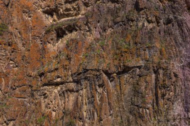 Dağlık bir bölgede engebeli kaya yüzeyi görkemli bir şekilde yükselir. Kalıplı yüzeyler ve sade ortamlar doğanın güzelliğini gün ışığında gözler önüne seriyor..