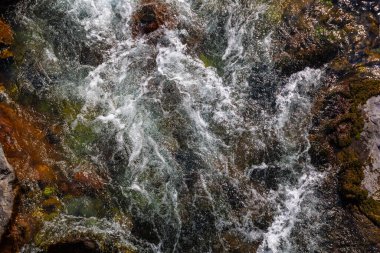 Enerji nehri su altındaki kayaların üzerinden akar, yüksek açılı manzara.