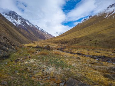 Uçsuz bucaksız dağlık Kırgızistan bölgesinde görkemli tepeler ve huzurlu bir vadi bulunur. Gündüz vakti, sakin ve sakin bir atmosfer oluşturan yumuşak bir akarsu arazide akar..