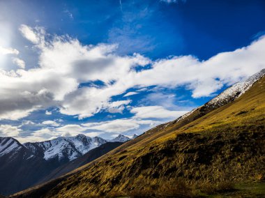 Serene Kırgızistan dağ manzarası açık mavi gökyüzünün altında görkemli tepeler sergiliyor. Barışçıl açık hava manzarası doğanın yansımasını ve hayranlığını davet eder güzellik..