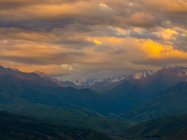Sakin günbatımı, karlı tepeler ve yemyeşil vadiler üzerinde çarpıcı renkler bırakır. Sakin atmosfer, doğanın güzelliğini yansıtmaya ve takdir etmeye davet eder..