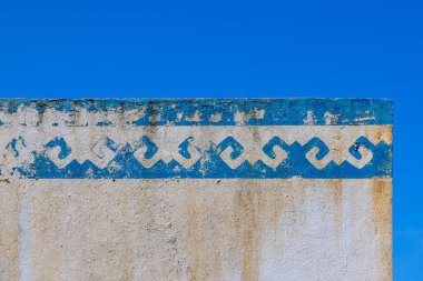 Yıpranmış duvar, dışarıda kabuk soyma desenli rustik boya sergiliyor. Açık gökyüzü, gündüz sahnesinin basit ve zamansız güzelliğini arttırır..