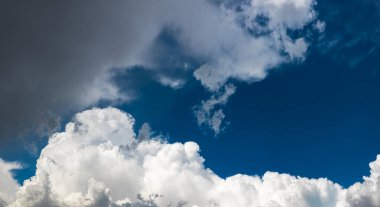 Seren bulutlar engin mavi gökyüzünde zarif bir şekilde süzülür. Açık hava manzarası doğanın güzelliğini yakalar ve bir sükunet hissi uyandırır..