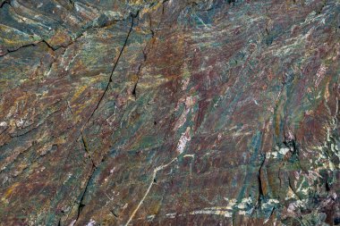 Mavi Altın Granit kabataslak bir yüzeyin detaylı görüntüsü. Mavi, altın, kahverengi ve gri kıvrımlı, kristal yapısı ve doğal çatlakları var..