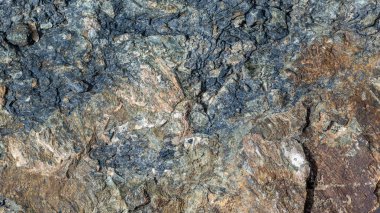 Yakın çekim, sert ve desenli kayaları doğal güneş ışığı altında yakalar. Toprak tonlar ve detaylar gündüz açık hava manzaralarının güzelliğini vurgular.