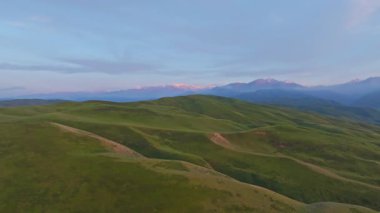Kırgızistan 'daki sakin dağların ve yeşil tepelerin üzerinde alacakaranlık. Dolly ileri hareketi ile drone görünümü.
