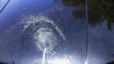 Güneşli bir günde kaputta akan su jeti açık havada yıkanırken ve durulanırken.