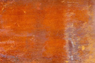 Turuncu ve kahverengi pas desenli metal bir yüzeye yakın çekim, korozyonun yoğunluğu ve dokusundaki değişimleri gösterir..