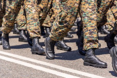 Askeri personel gündüz yürüyüşü sırasında kaldırımlı bir yol boyunca organize bir şekilde yürür..