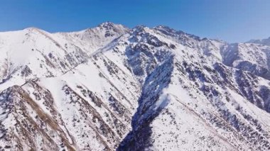 Kırgızistan 'da kış günü hava manzarası karla kaplı dağları yakalar. Dolly ileri kamera hareketi.